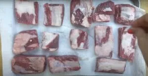 Raw beef short ribs seasoned with salt, arranged on paper towels for preparation.